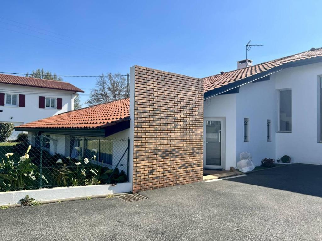 een bakstenen muur naast een wit gebouw met een garage bij Appartement Cambo-les-Bains, 3 pièces, 4 personnes - FR-1-495-21 in Cambo-les-Bains