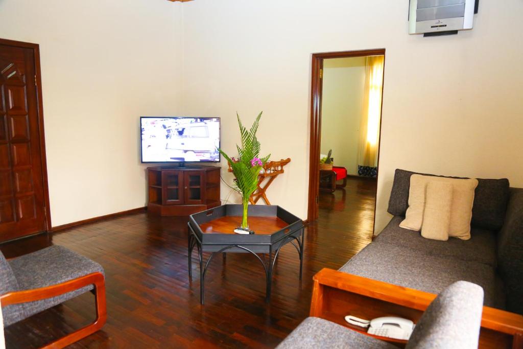 a living room with a couch and a tv at Coconut Grove Regency Hotel in Accra