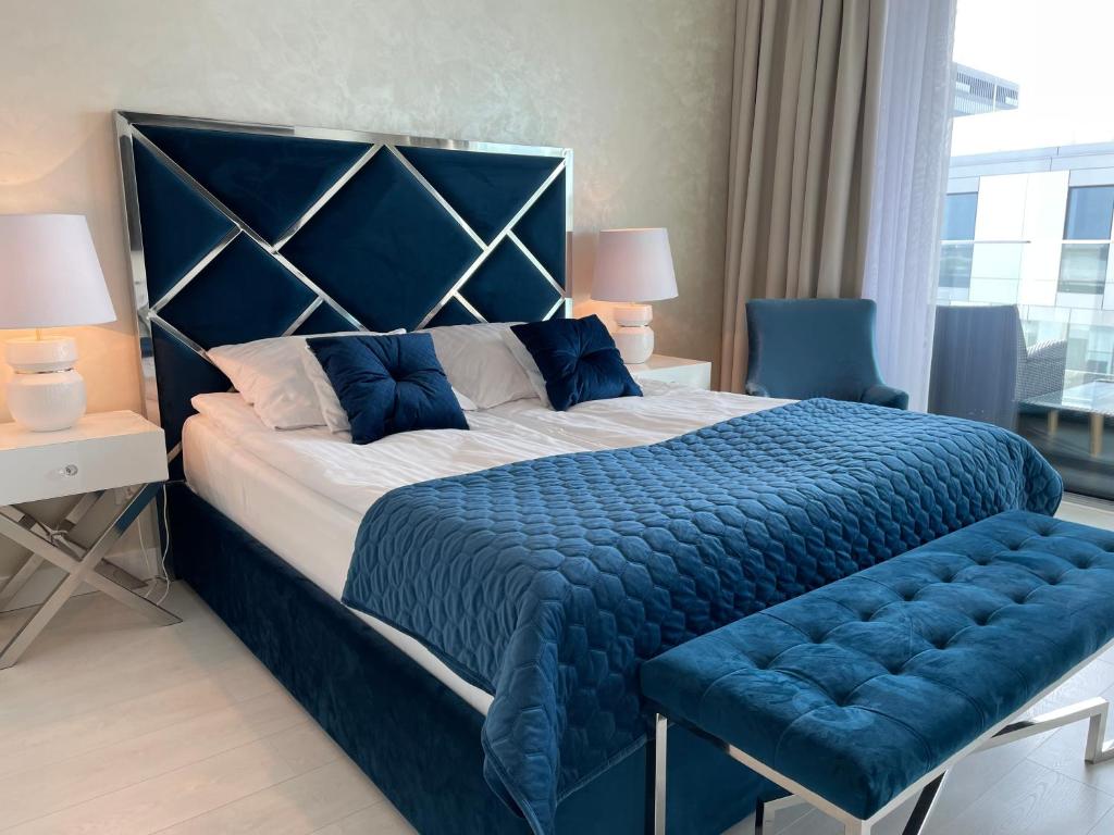 1 cama grande con edredón azul y banco azul en Apartament Faltom Gdynia Yacht Park, en Gdynia