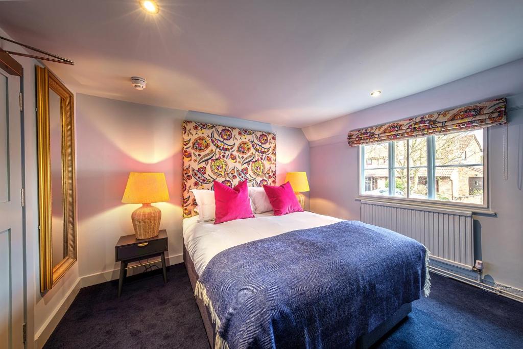 a bedroom with a bed with pink pillows and a window at The Carpenters Arms in Great Wilbraham