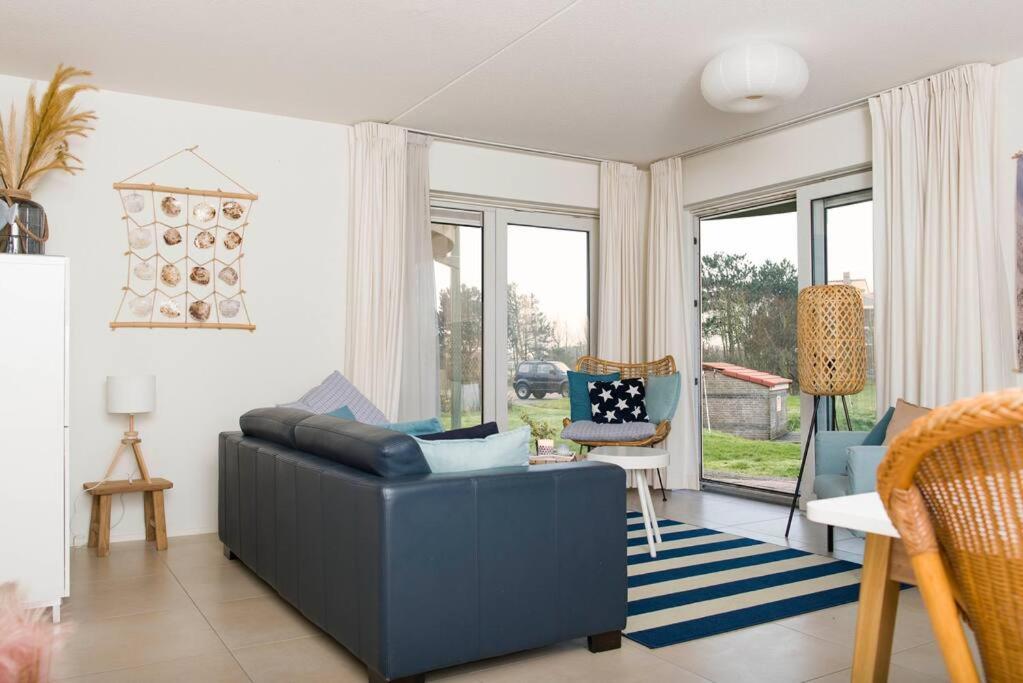 ein Wohnzimmer mit einem blauen Sofa und einigen Fenstern in der Unterkunft Residence Juliana 14 Julianadorp aan zee in Julianadorp