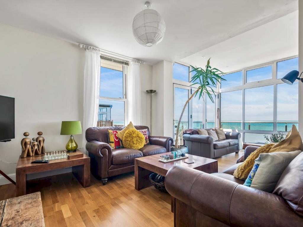 a living room with leather furniture and a large window at Pass the Keys Jarrahdale Beach House - Stunning Luxurious Holiday Pad by the sea in Herne Bay