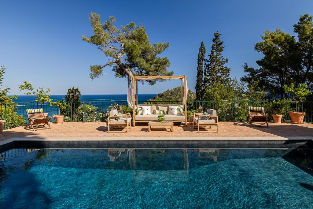 een zwembad met een bank en stoelen naast een trouwring bij Extraordinary view with a Cobalt pool on the Tuscany coast in Porto Ercole
