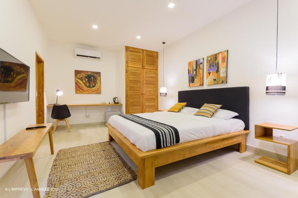 a bedroom with a king sized bed and a desk at L'imprévu L'annexe in Cotonou