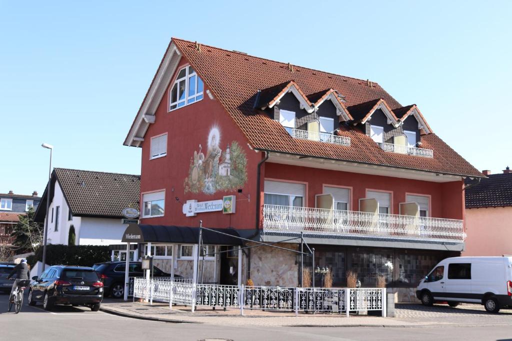een groot rood gebouw met een wit hek ervoor bij Hotel Weinhaus Wiedemann in Ginsheim-Gustavsburg