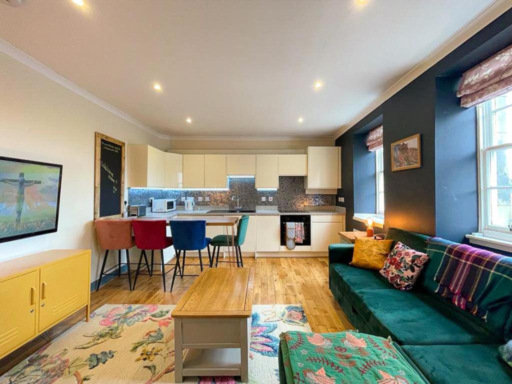 a living room with a green couch and a kitchen at Lively & Energetic 2BR on The Royal Mile in Edinburgh