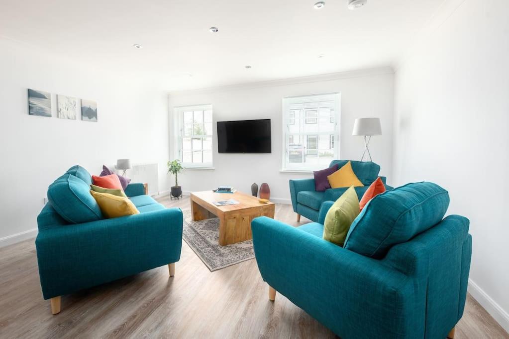 a living room with two blue chairs and a table at Modern Ground Floor Apartment in Tornagrain in Inverness