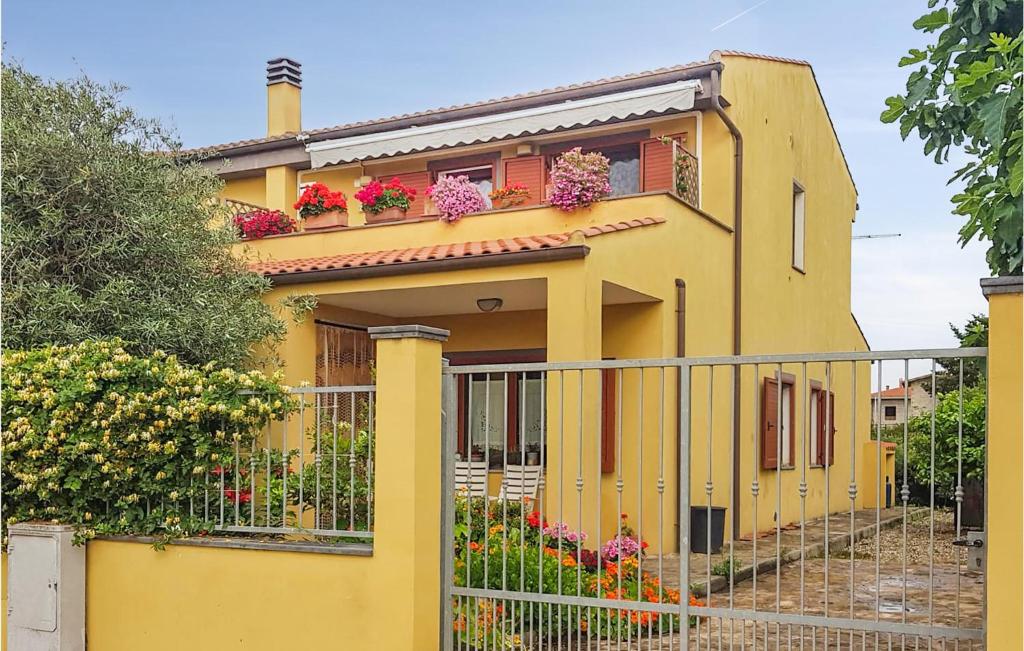 a yellow house with flowers on the balcony at Beautiful Apartment In Riola Sardo With Wifi And 2 Bedrooms in Riola Sardo