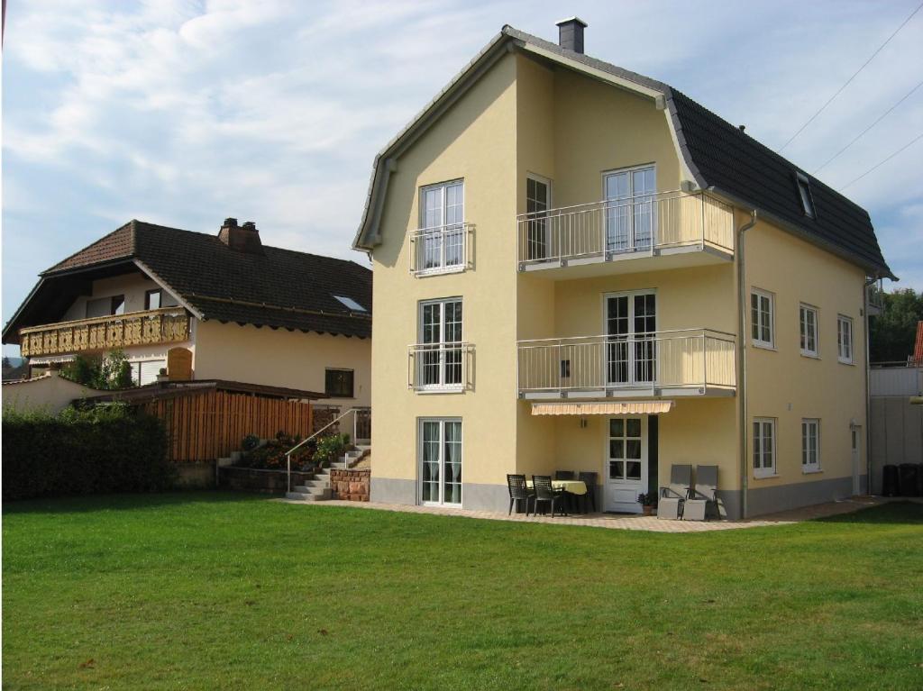 una grande casa gialla con un prato davanti di Schöne Ferienwohnung in Fischbach / Pfälzer Wald a Fischbach