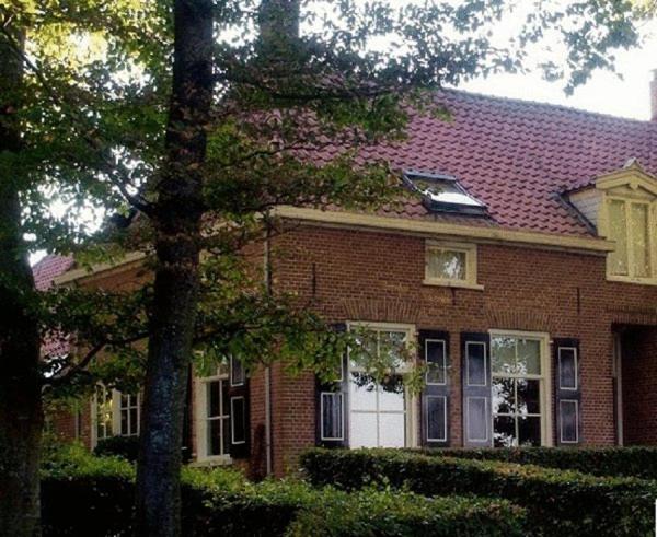 een bruin bakstenen huis met een rood dak bij B&B Buitenplaats Natuurlijk Goed in Oosterwolde