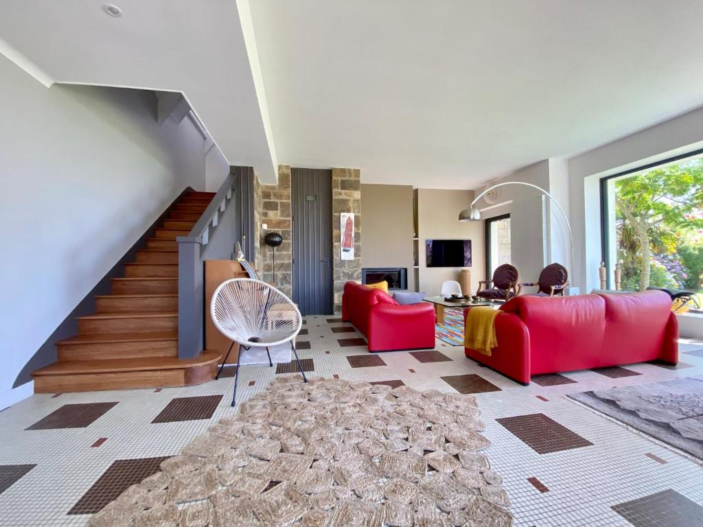 una sala de estar con muebles de color rojo y una escalera en Superbe villa vue sur mer, corniche de la plage en Bénodet