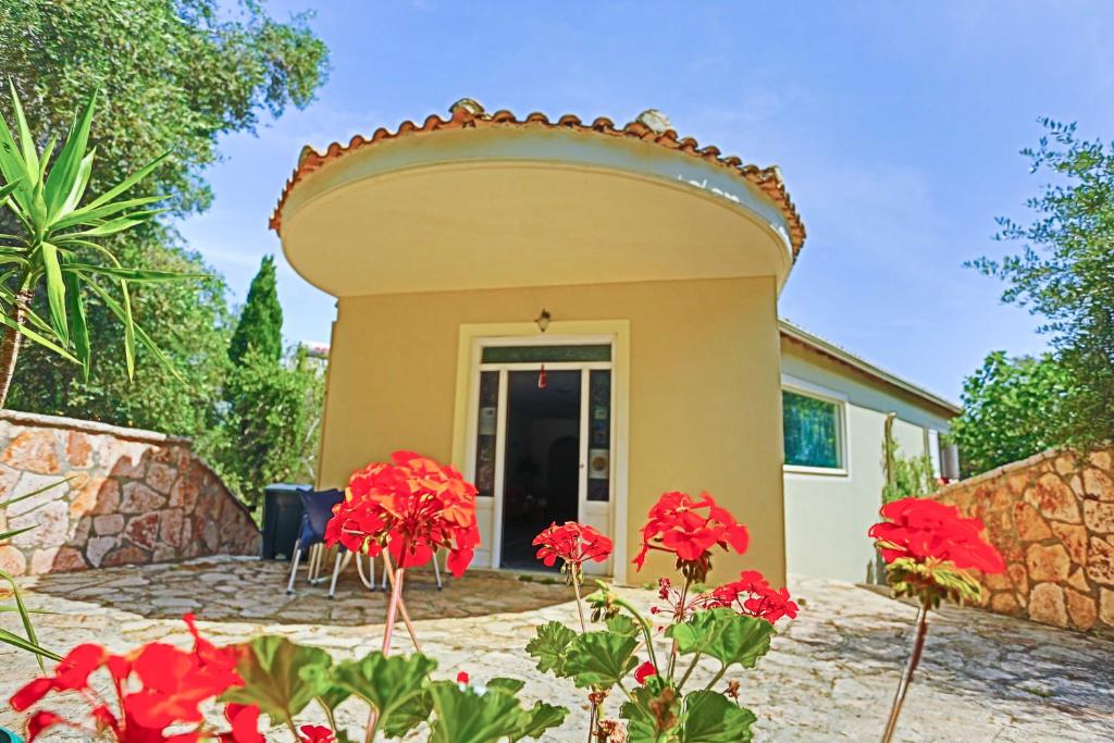 een villa met een patio en rode bloemen bij Amfitriti Hotel & Studios in Lákka