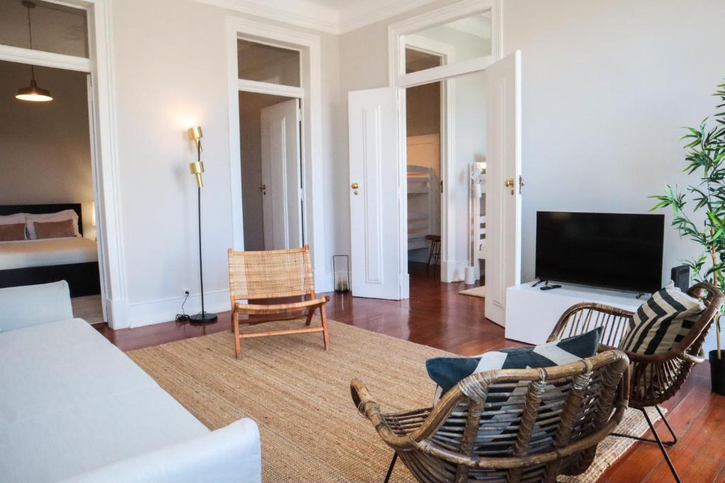 een woonkamer met een bank en stoelen en een televisie bij The Residences at Bairro Alto in Lissabon