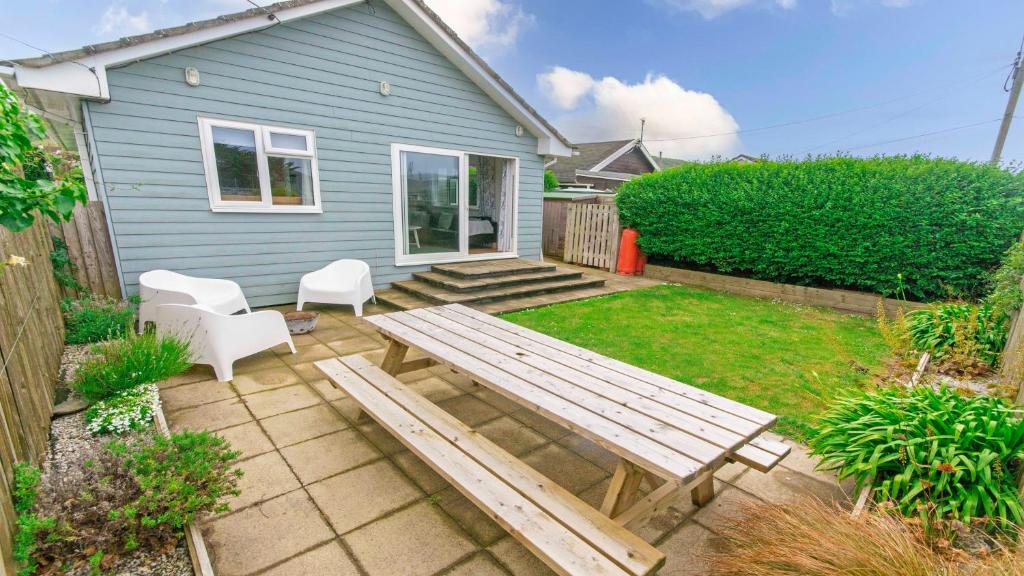 a backyard with a wooden picnic table and chairs at Swallows Croyde - Open plan beach chalet & close proximity to the beach - Sleeps 6 in Croyde