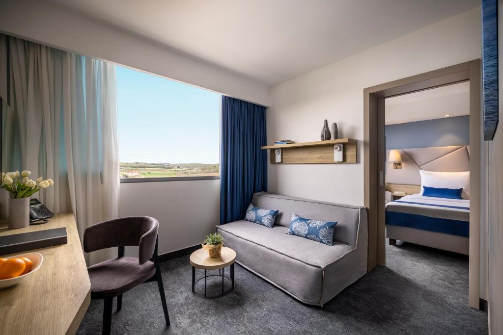 a hotel room with a couch and a bed at Valamar Diamant Hotel in Poreč