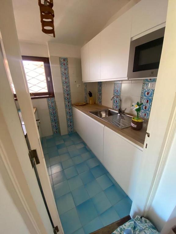 małą kuchnię ze zlewem i niebieską podłogą wyłożoną kafelkami w obiekcie GG Luxury Apartments - Porto Cervo - Costa Smeralda w mieście Porto Cervo