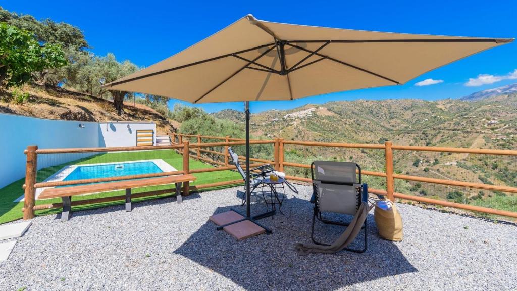 a patio with an umbrella and chairs and a pool at Villa Cinco Soles Árchez by Ruralidays in Árchez