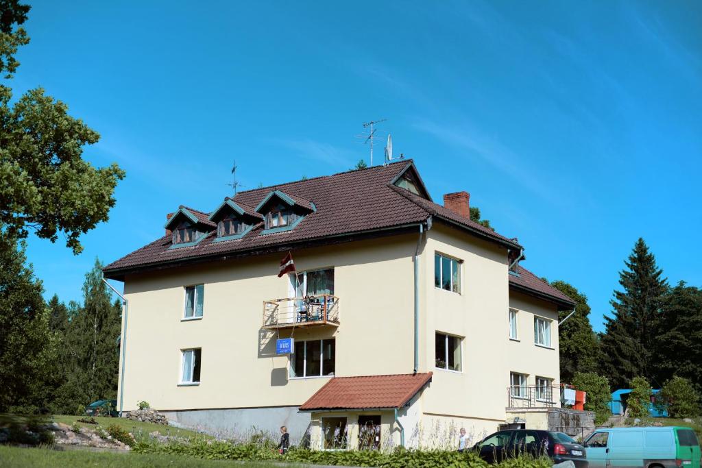 duży biały dom z brązowym dachem w obiekcie Atpūtas centrs Paideri w mieście Alūksne