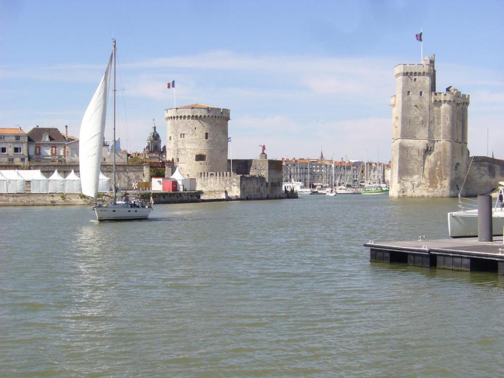 un velero en el agua junto a un castillo en Joli studio meublé + parking en sous sol, en La Rochelle