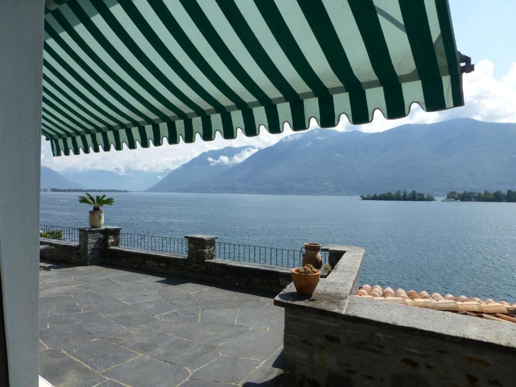uma vista para a água a partir de um pátio com um guarda-chuva em Casa Chatelain em Ronco sopra Ascona