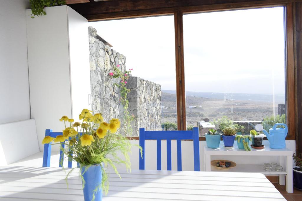 einen Tisch mit blauen Stühlen und eine Vase mit Blumen darauf in der Unterkunft Casa SocAire. Naturaleza, mar, paz, relax. in Tabayesco