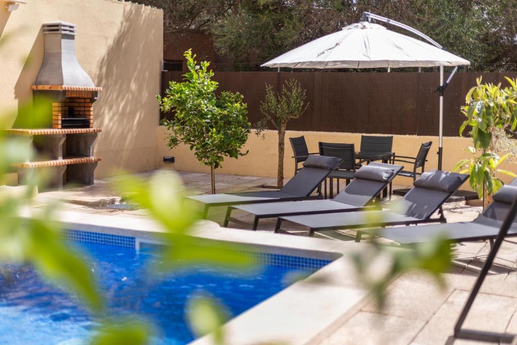 a group of chairs and an umbrella next to a pool at Calamar 7 in Portocolom