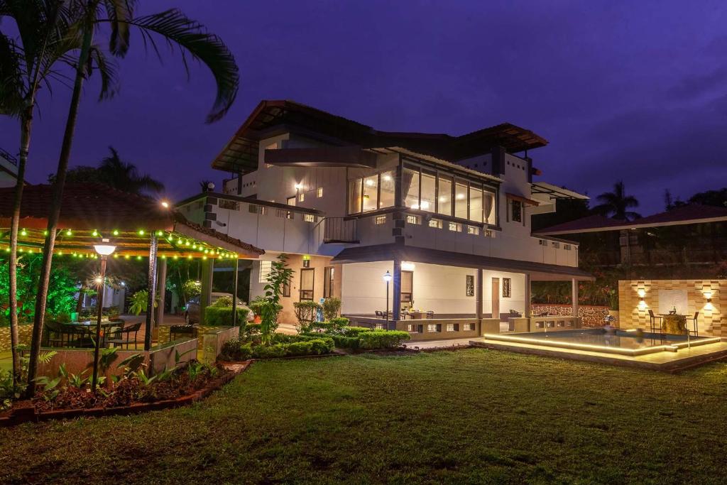una gran casa blanca con un patio por la noche en Sunshine Bloom by VEO - Part of StayVista, en Lonavala