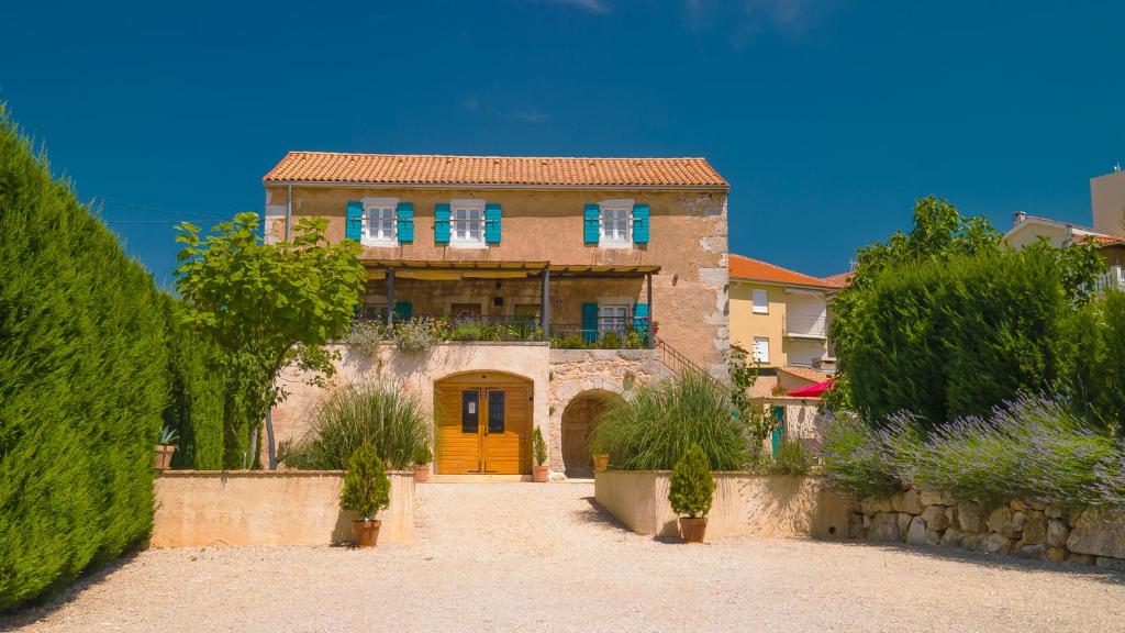 a large house with a yellow door in a yard at Villa Ca'Pietra, rustic stone house in Malinska