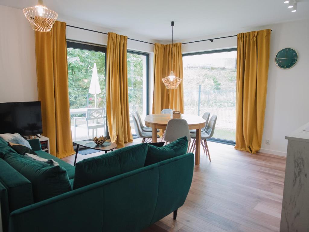 a living room with a green couch and a table at Apartament Nad Strumykiem z ogródkiem - Dream Apart in Ustroń