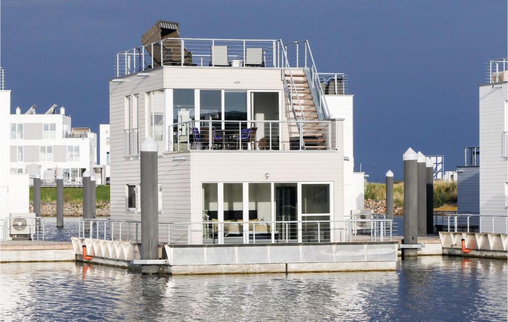 a white house on the water next to some buildings at Nice Ship In Ostseeresort Olpenitz With Kitchen in Olpenitz