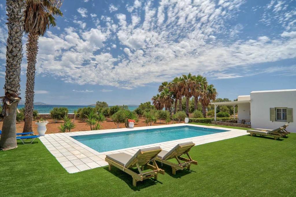 una piscina con 2 sillas y una casa en Sunrise Luxury Apartments & Suites, en Antíparos