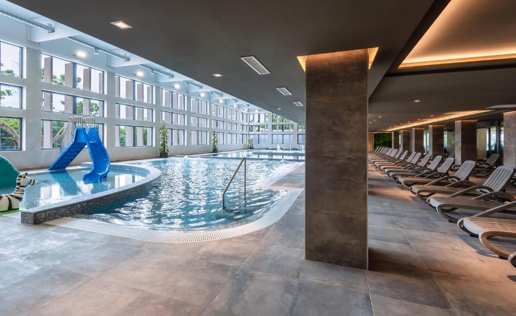 basen w holu z krzesłami i zjeżdżalnią w obiekcie Hunguest Hotel Bál Resort w mieście Balatonalmádi