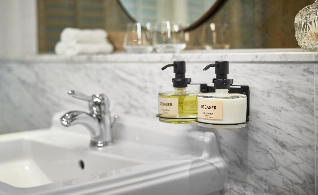 two bottles of soap sitting on a bathroom sink at Pulitzer Amsterdam in Amsterdam