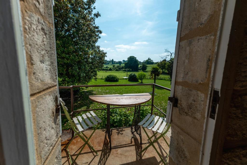 una mesa y sillas en un balcón con vistas en Suite campagnarde près Bordeaux, vue sur les vignes au Château Camponac, en Bourg-sur-Gironde