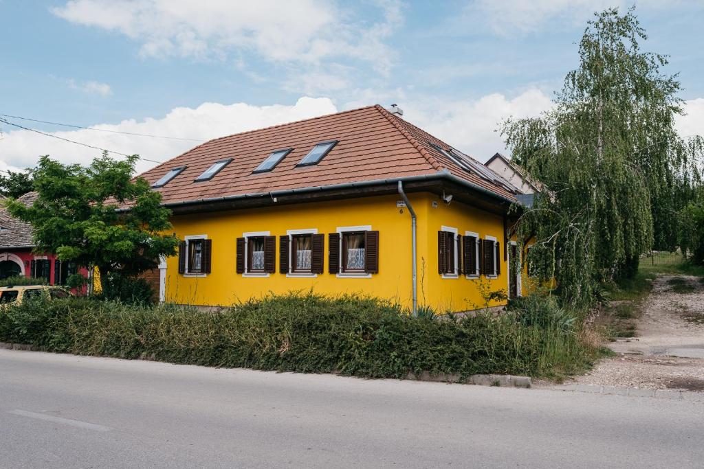 una casa amarilla con techo marrón en una calle en Hemina Vendégház, en Tata