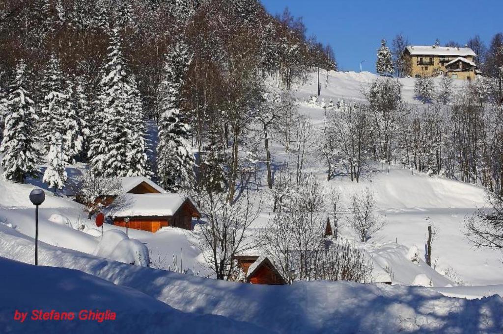 una ladera cubierta de nieve con una casa y árboles en Camping Yoghi e Bubu, en San Giacomo