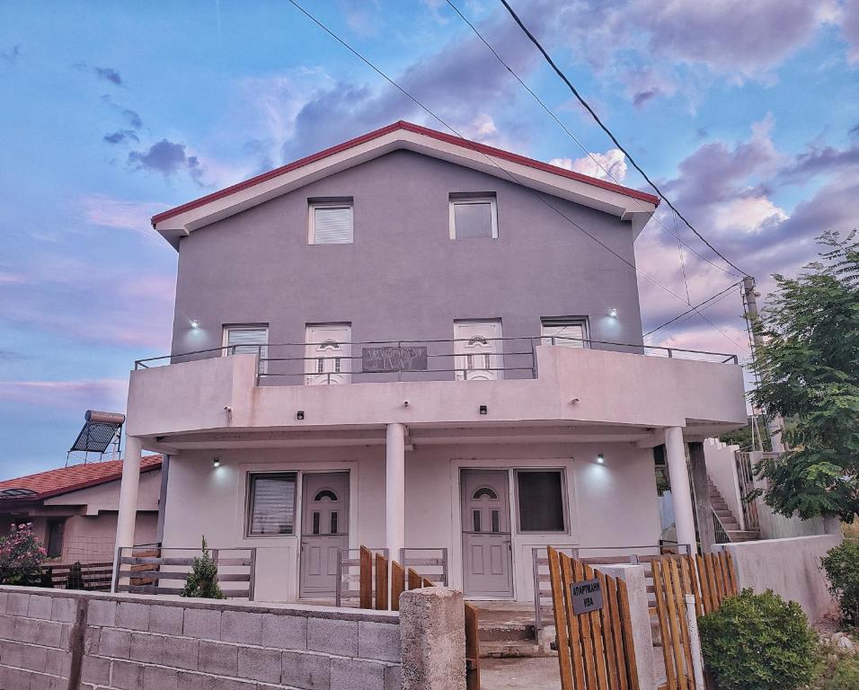 uma casa branca com uma cerca à frente. em Apartments Iva em Star Dojran