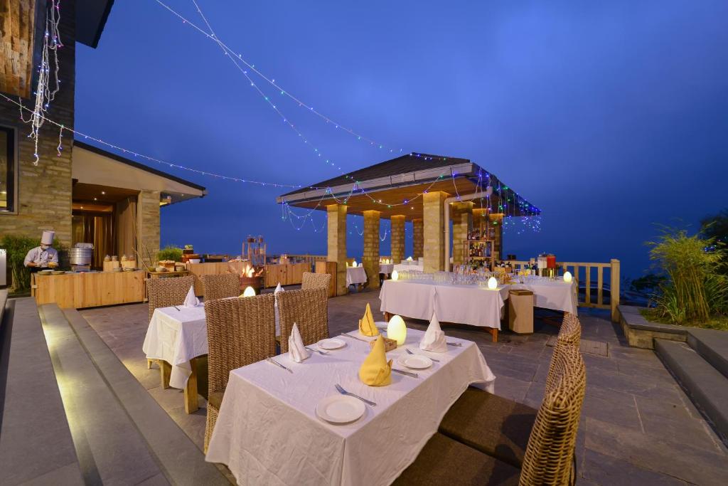 a restaurant with white tables and chairs at night at Sarangkot Mountain Lodge in Pokhara