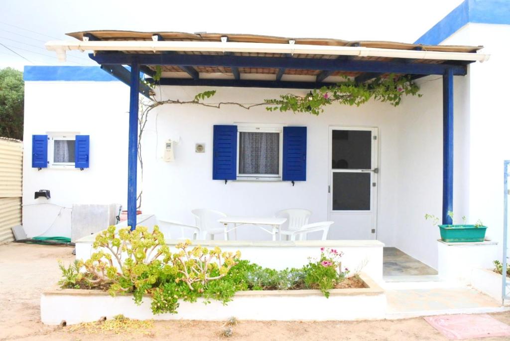 a white house with blue shutters and white chairs at Fabrika's Breeze in Vari