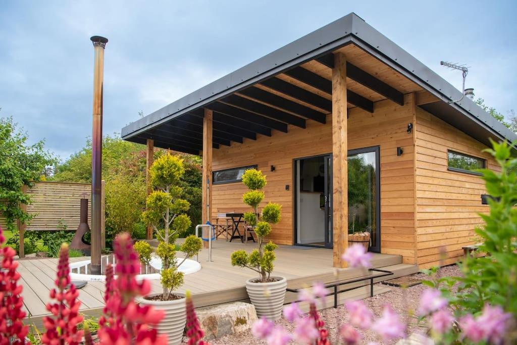 a small wooden cabin with a deck with plants at Peaceful Bothy Retreat in Nairn