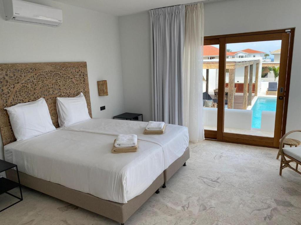 a bedroom with a bed and a balcony with a pool at Villa Ban Kas Curaçao in Jan Thiel
