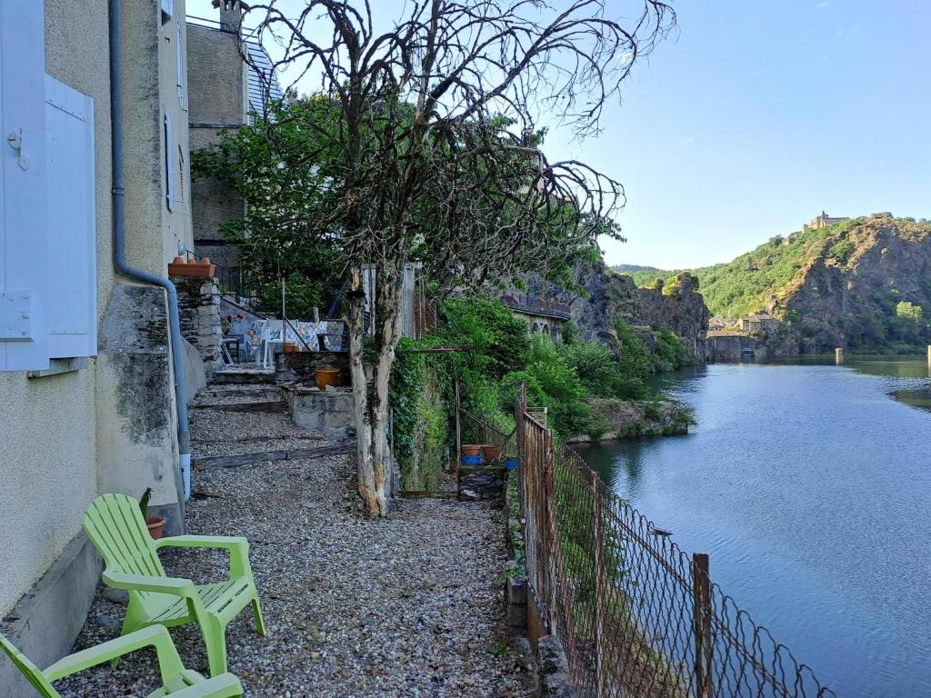 a house with two green chairs next to a river at Les Reflets du Tarn in Ambialet