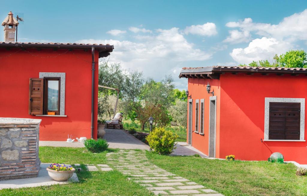 une maison rouge avec un chemin entre deux bâtiments dans l'établissement Agriturismo Poggio Degli Ulivi, à Bomarzo