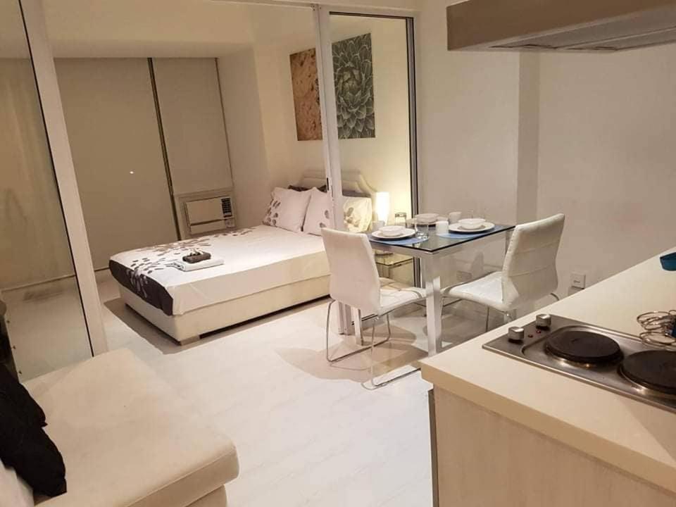 a bedroom with a bed and a table and a kitchen at Modern 1br unit azure residences in Manila