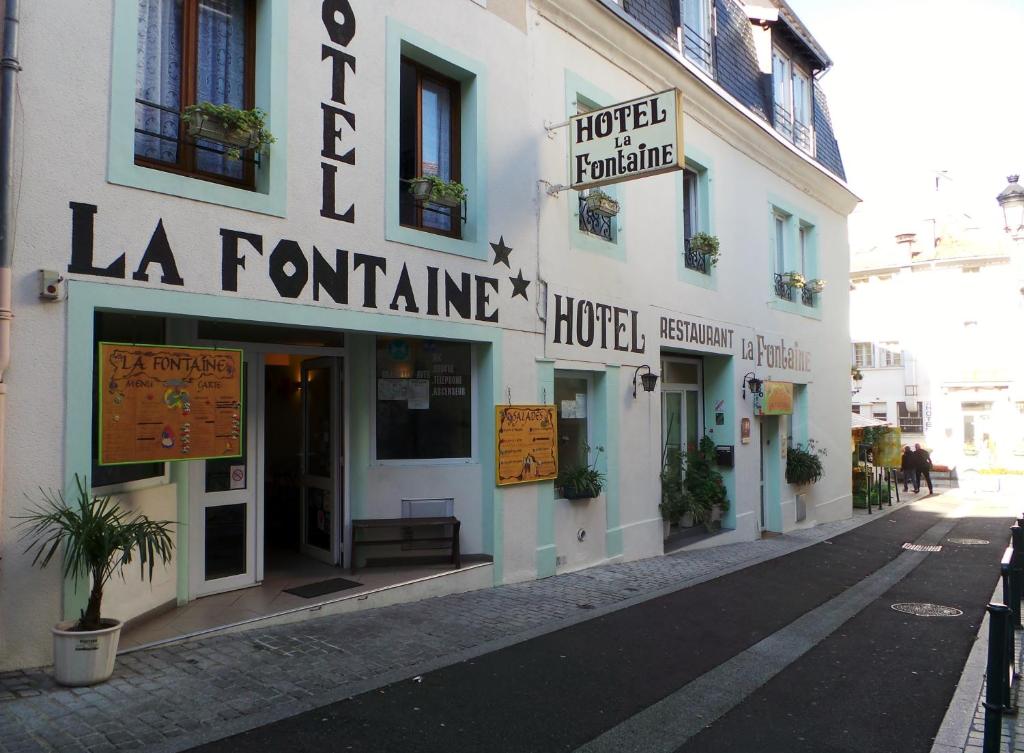 a building with signs on the side of a street at Hôtel La Fontaine in Lourdes