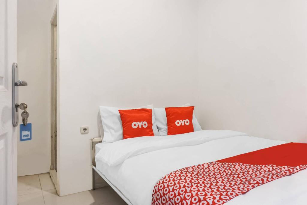 ein weißes Bett mit zwei roten Kissen darauf in der Unterkunft Super OYO 91074 Stariez Senen Syariah in Jakarta