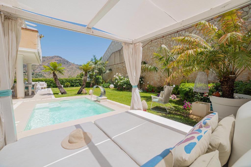 a patio with a pool and a table and chairs at Villa Mastrissa Taormina in Taormina