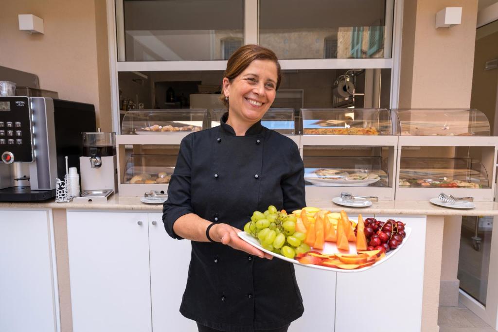 a woman holding a plate of fruit and vegetables at ELISEO PALACE TROPEA in Tropea