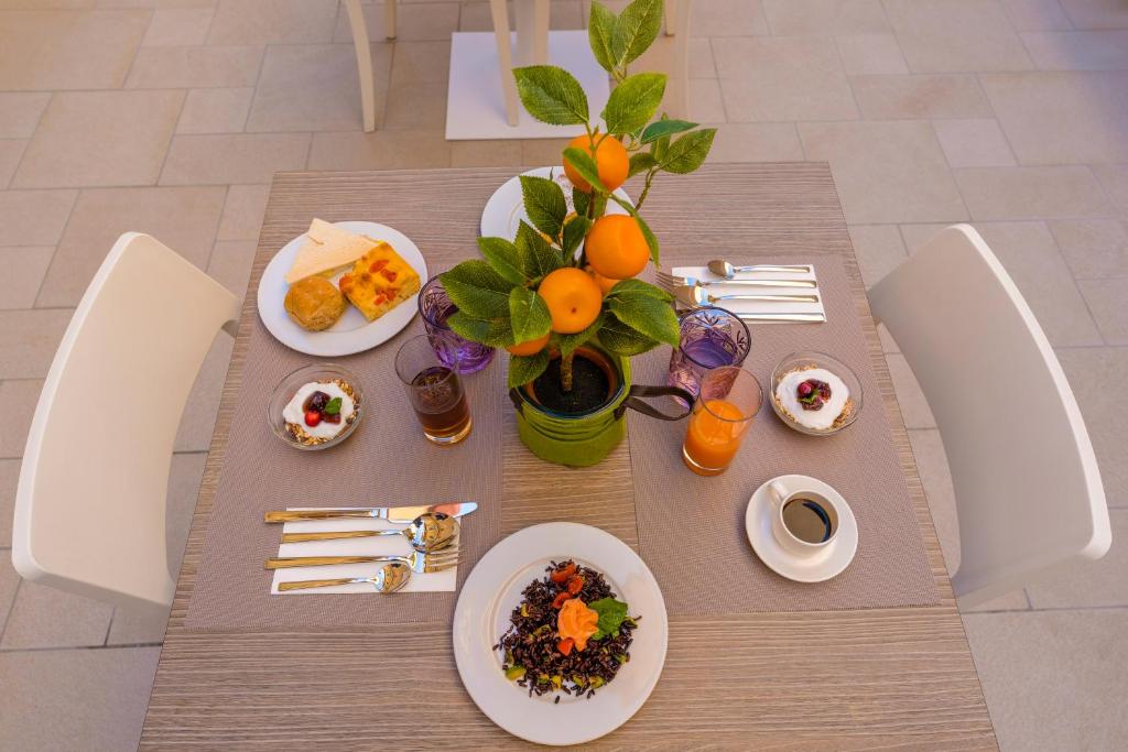 a table with plates of food and a vase of oranges at ELISEO PALACE TROPEA in Tropea