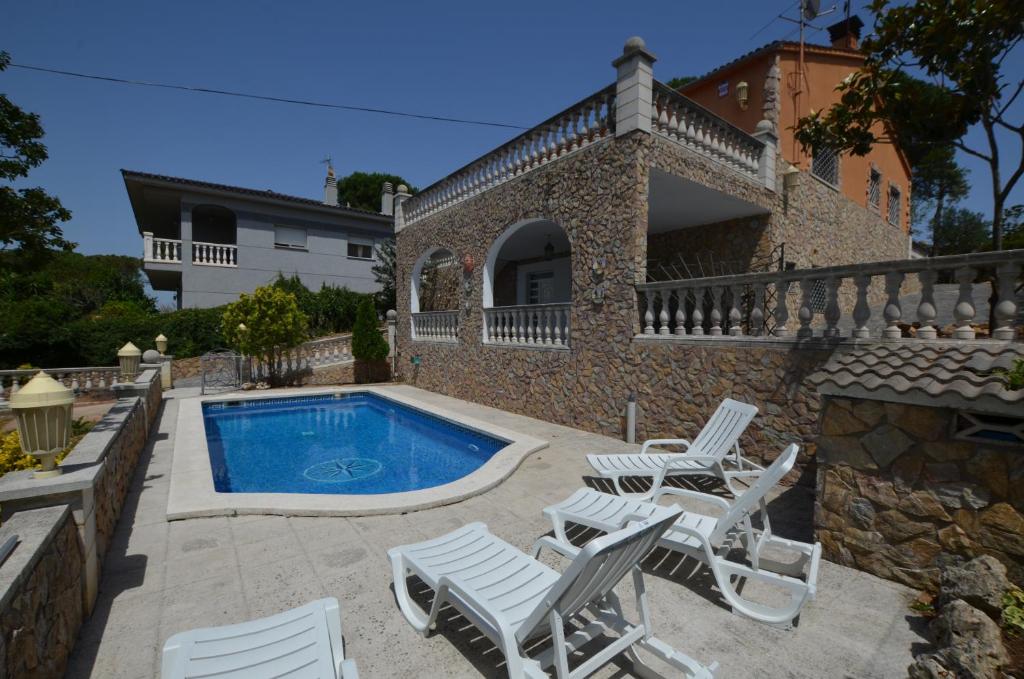 une villa avec une piscine, des chaises et une maison dans l'établissement Villa Rosa 10 Personas Montbarbat Costa Brava, à Maçanet de la Selva